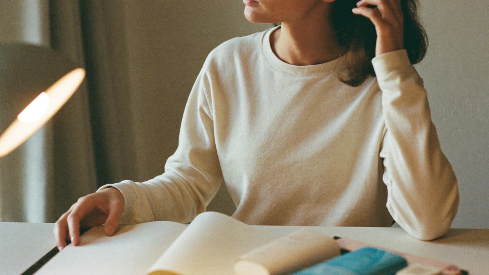 Person sitzt konzentriert am Schreibtisch zwischen aufgeschlagenen Notizbüchern — symbolisch für Fokus und Struktur bei ADHS