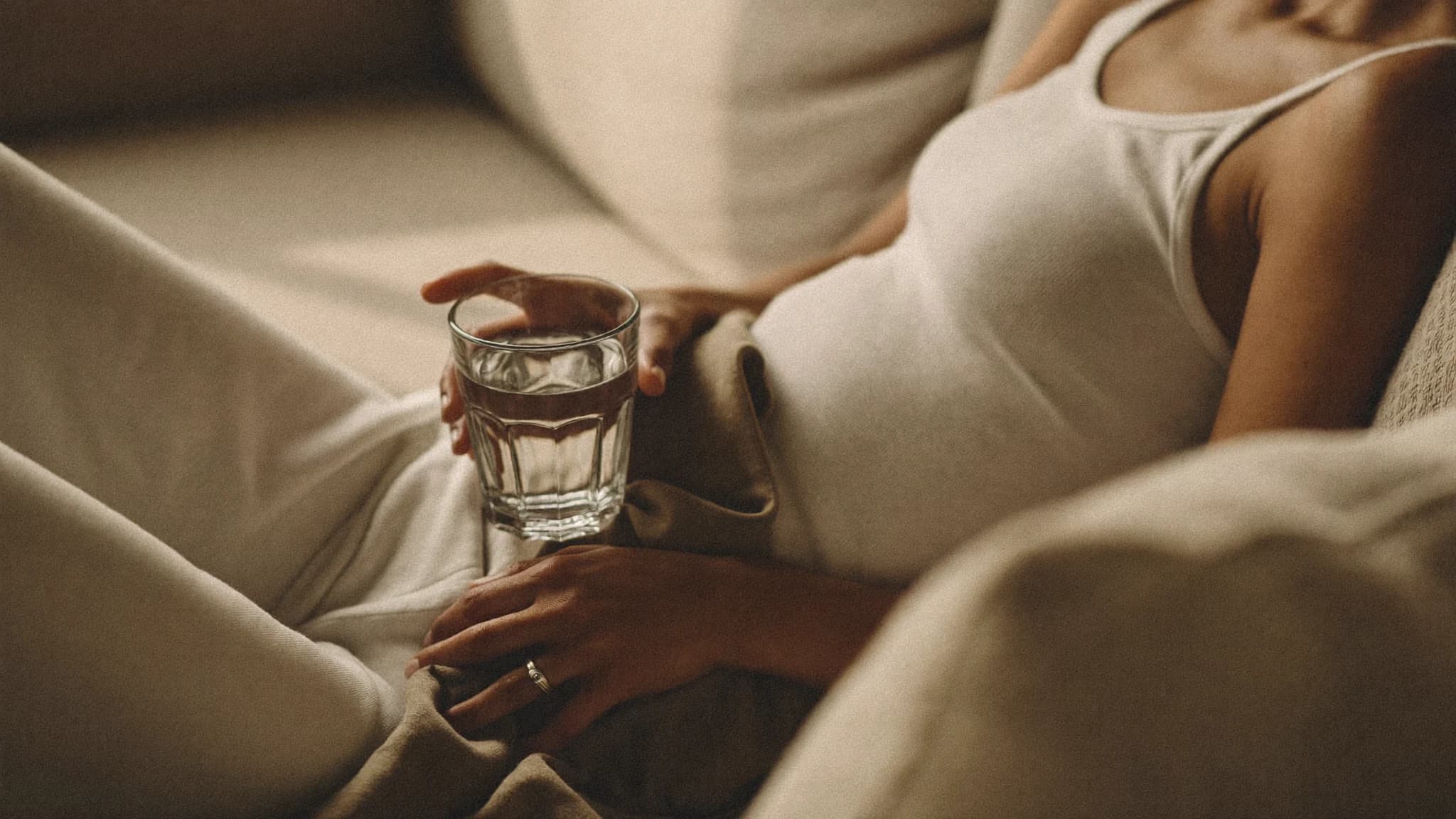 Person ruht sich mit einem Glas Wasser auf dem Sofa aus — symbolisch für einen selbstbestimmten Alltag mit Epilepsie