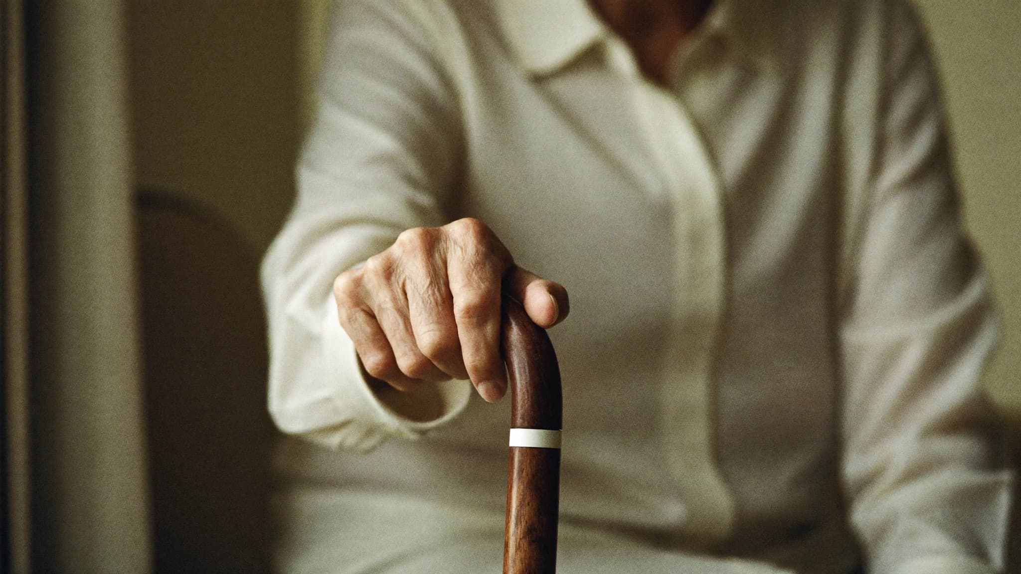 Hand einer älteren Person ruht auf dem Griff eines Gehstocks — symbolisch für Beweglichkeit bei Parkinson